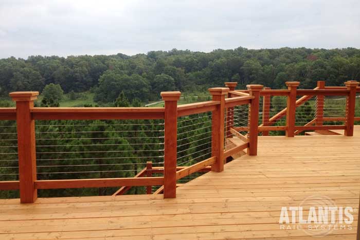Wooden Top Rail on a Cable Railing system on deck overlooking a green forest.